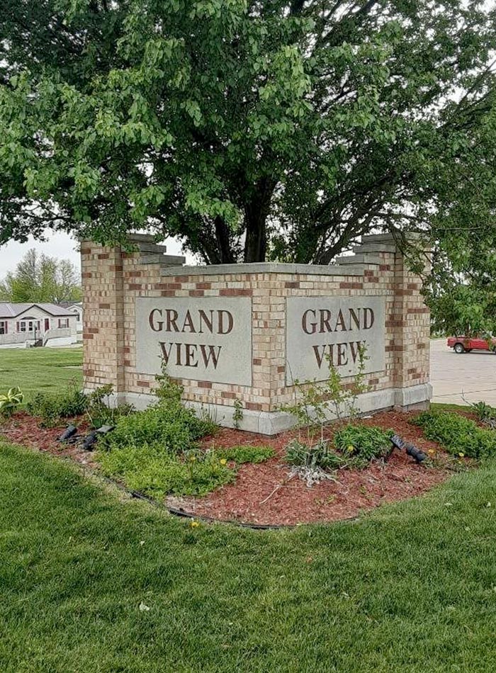 The Grand View sign bricked around a lush growing green tree